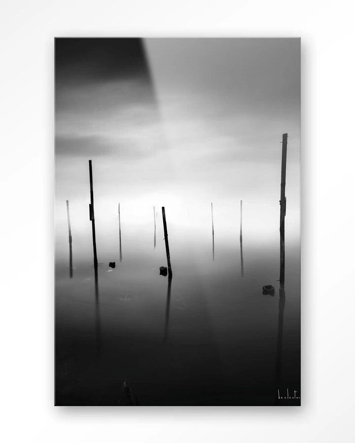 Kunsttrykk på syrefritt papir, lerret og glass. Svart-hvit foto av påler eller stokker som stikker opp fra en sjø. 