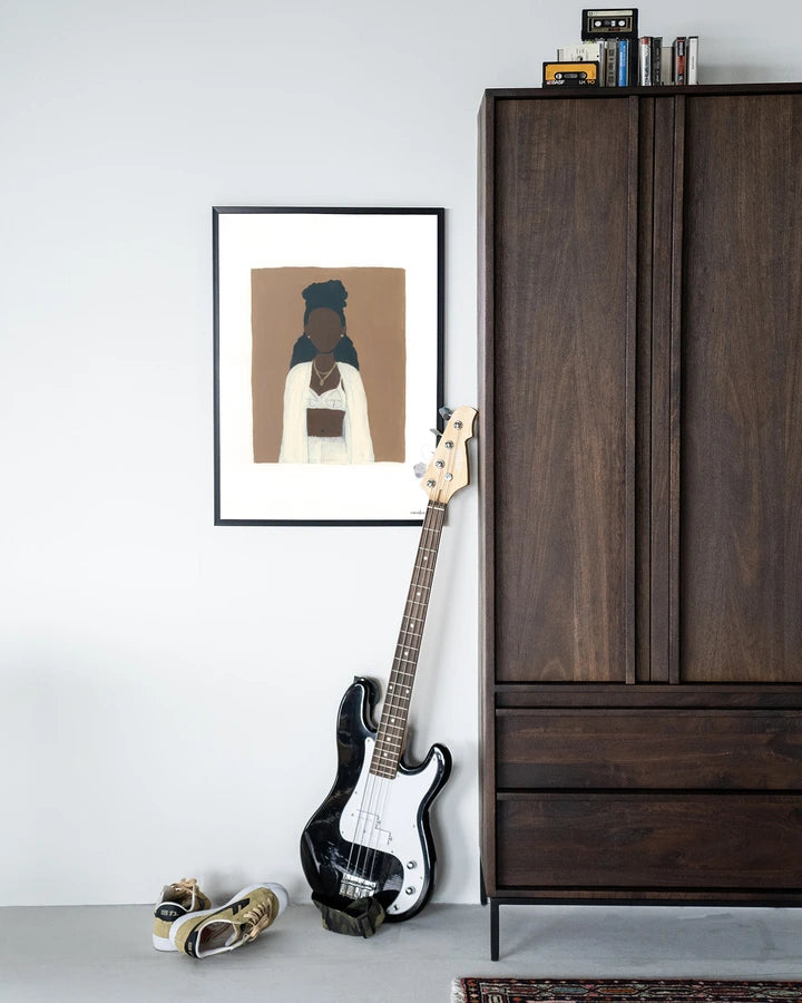 Kunsttrykk i ramme på vegg ved siden av skap i mørkt treverk.