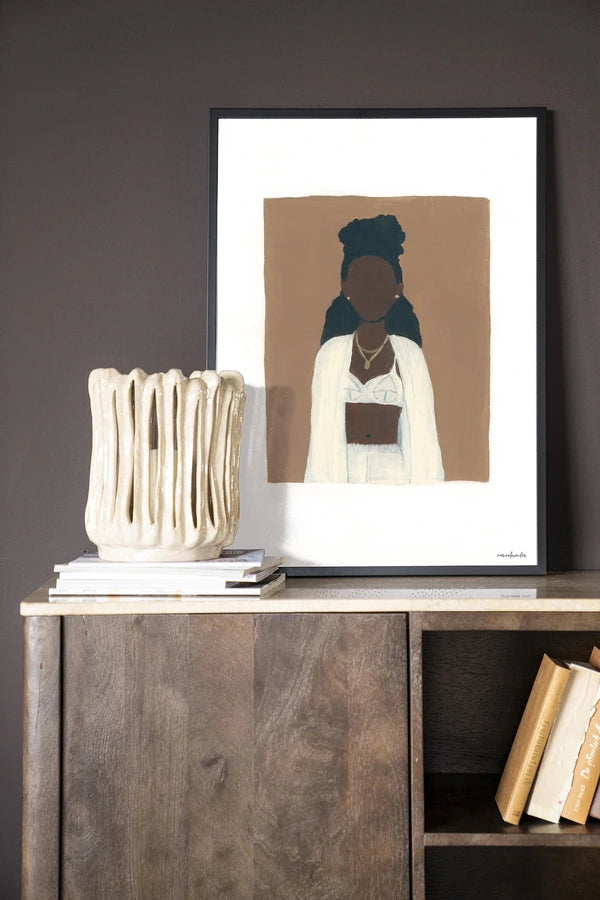 Miljøbilde med skap i mørkt treverk og kunsttrykk i ramme.