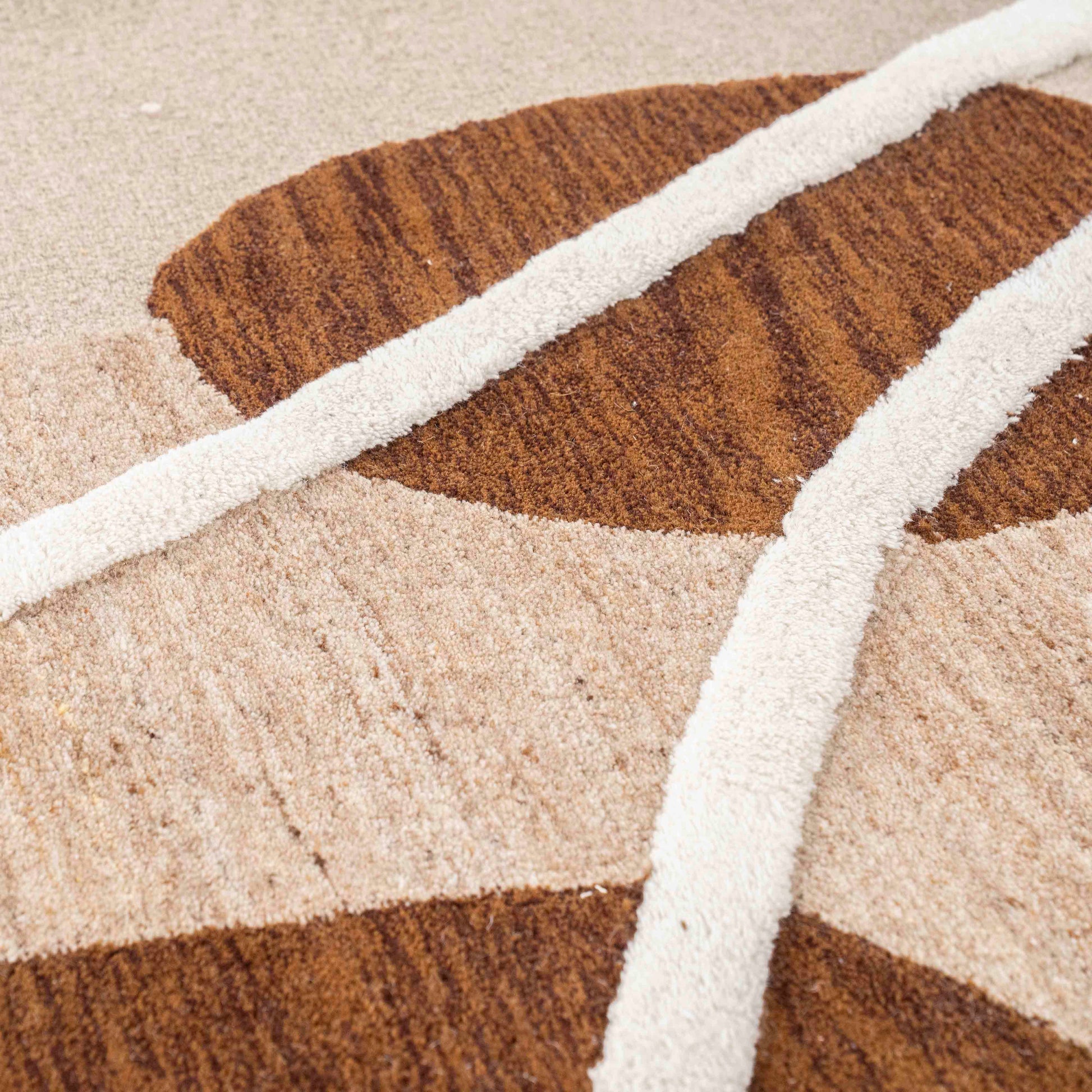 Gulvteppe i organiske former. Beige grrunnfarge med brune og hvite fargeflater.