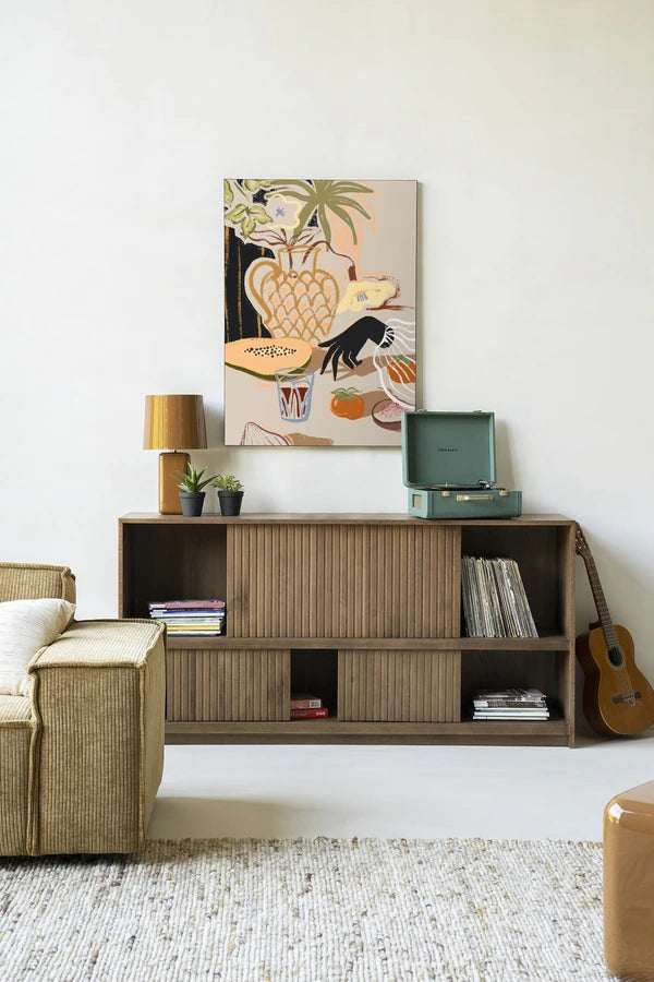 Kunsttrykk på syrefritt papir, lerret og glass. Motiv: et dekket bord med blomster, frukt og grønnsaker og en hånd som trer inn i bildet.