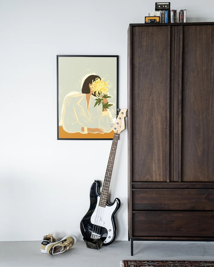 Kunsttrykk på syrefritt papir, lerret og glass. Motiv: kvinnesom holder skjuler ansiktet bak en stor, gul blomst. Lys fargepalett.