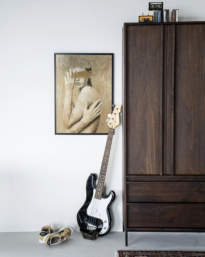 Miljøbilde med skap i mørkt treverk og kunsttrykk i ramme.