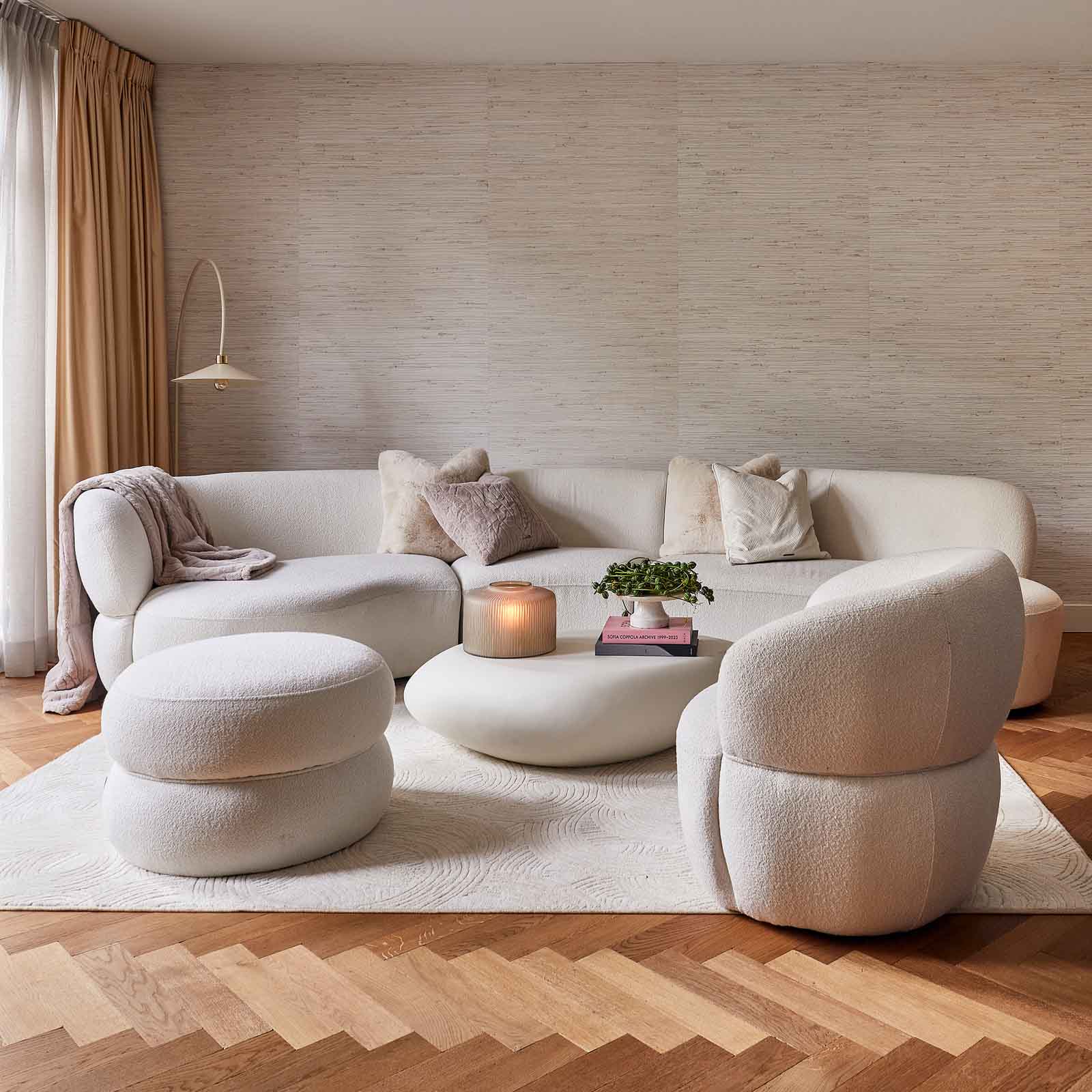 Miljøbilde: Hvit buet sofa 3-seter i myke, organiske former. Lenestol og puff i Bouclé-stoff