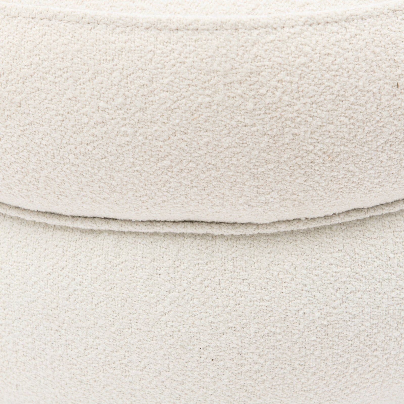 Nærbilde av rund og lys beige bouclé puff.