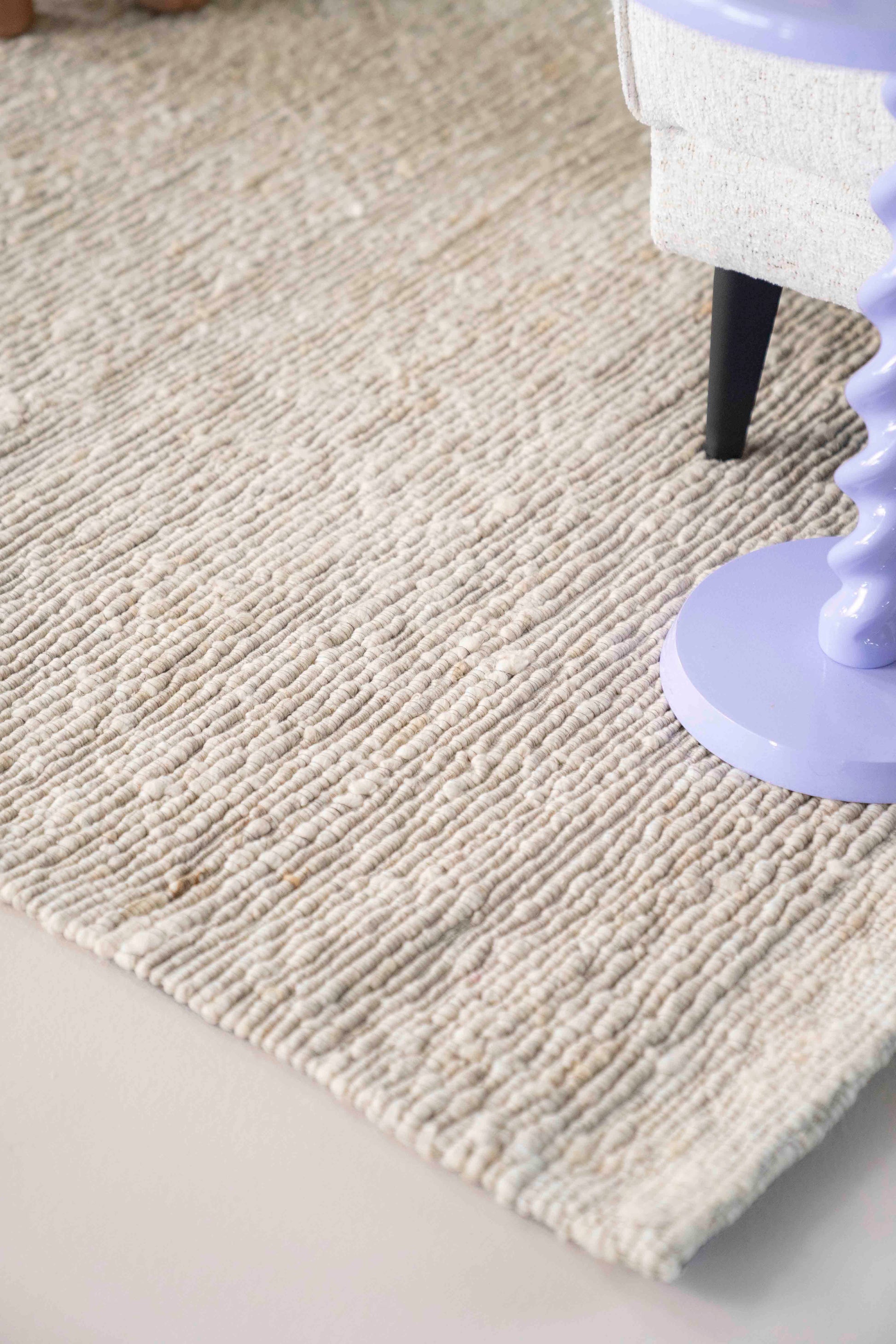 Lyst kremfarget gulvteppe i vevd ull.