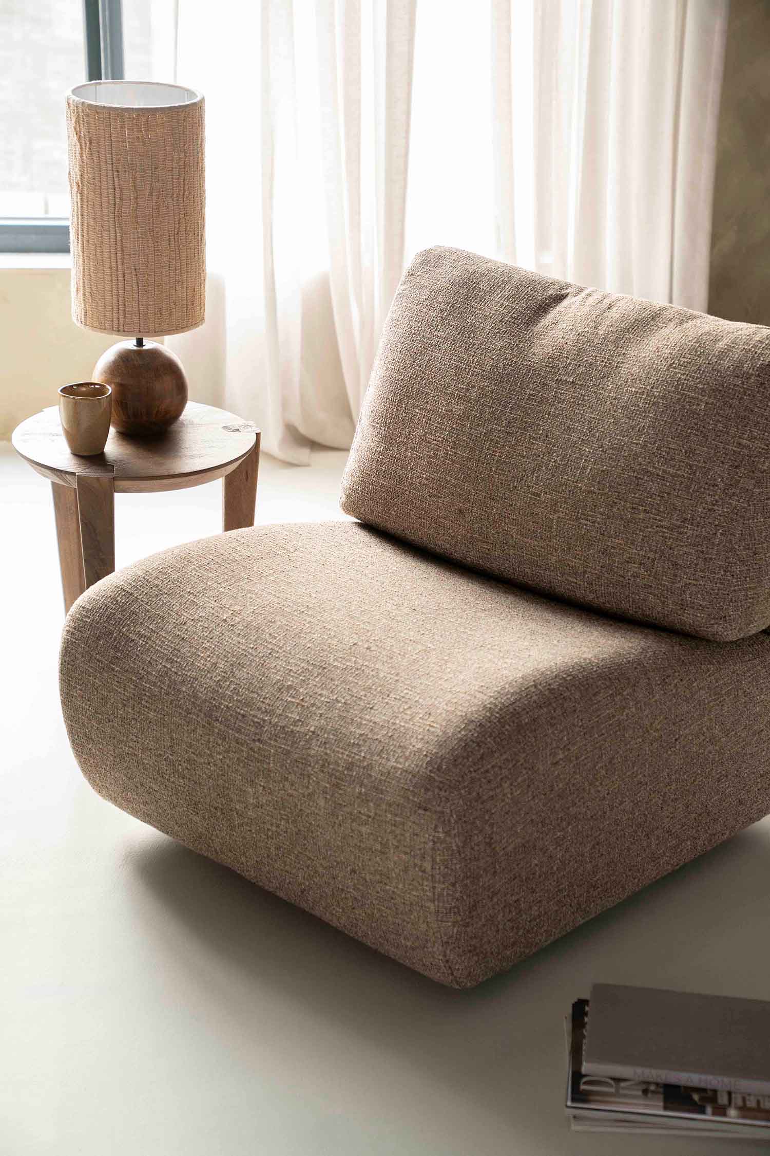 Lucia lounge-stol i brunt tekstil. Lenestol uten armlene.